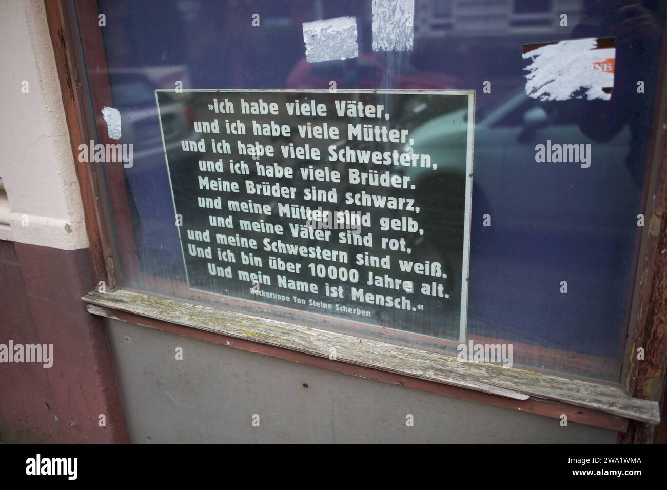 Flensburg, Schleswig-Holstein, Bilder vom Morgen nach der Silvesternacht 2023/2024. Bilderrahmen hinter Fenster, Text von der Band ton Steine Scherben: ICH habe viele Väter, ich habe viele Mütter und ich habe viele Schwestern und ich habe viele Brüder meine Väter sind schwarz und meine Brüder sind gelb meine Mütter sind rot und meine Schwestern sind hell ICH bin über zehntausend Jahre alt und mein Nom ist Mensch. Aufnahmne vom 01.01.2024, Flensburg-Sandberg, Bahnhofsumfeld, *** Flensburg, Schleswig Holstein, photos du matin après la Saint-Sylvestre 2023 2024 cadre photo derrière la fenêtre, Banque D'Images
