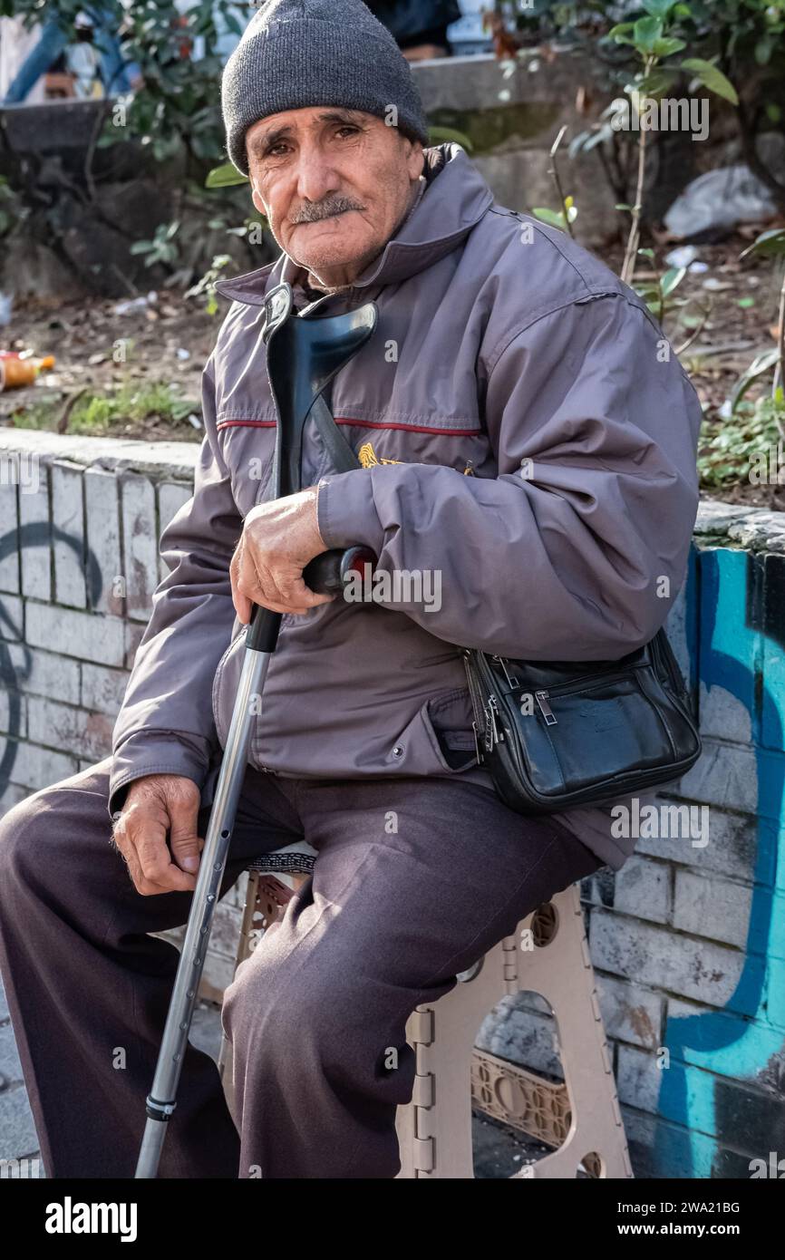 Homme âgé assis avec une canne sur un banc de rue. Portrait d'homme âgé très vieux. Concept de solitude et vieillesse solitaire. Istanbul Turquie-décembre 24, Banque D'Images