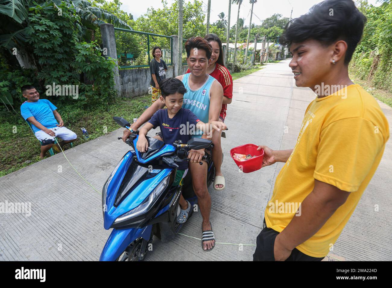 Tiaong, Philippines. 1 janvier 2024 : dans les provinces rurales, les familles pauvres Philippines mettent en place des routes à péage amicales avec une corde et un signe de bonne année. Les voitures, les tricycles ou les piétons sont encouragés à faire des dons de remerciement, généralement seulement quelques pesos, sans obligation, toujours avec le sourire et parfois embellis avec peu de pas de danse. Une tradition qui n’a été pratiquée que dans certaines régions et qui s’est propagée à presque tout le pays depuis les jours difficiles de l’épidémie de COVID 19. Par exemple, sur plus de 1 km, à certains endroits, vous pouvez compter jusqu’à quinze arrêts. Crédit : Kevin Izorce/Alamy Live News Banque D'Images