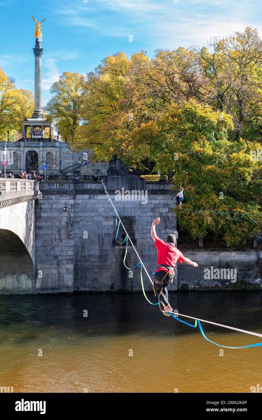 Deux hommes en équilibre sur des slacklines au-dessus de l'Isar au pont Luitpold sous le soleil d'automne, Munich, Bavière, Allemagne Banque D'Images