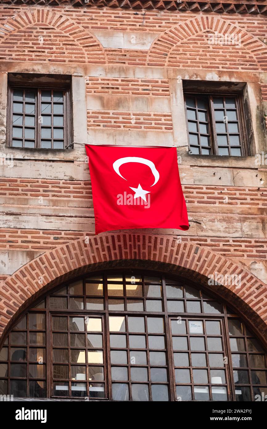 Le drapeau turc agite au-dessus du bâtiment d'architecture de style ancien. Drapeau turc accroché sur la maison entre les fenêtres. Photo de voyage, photo de rue Banque D'Images