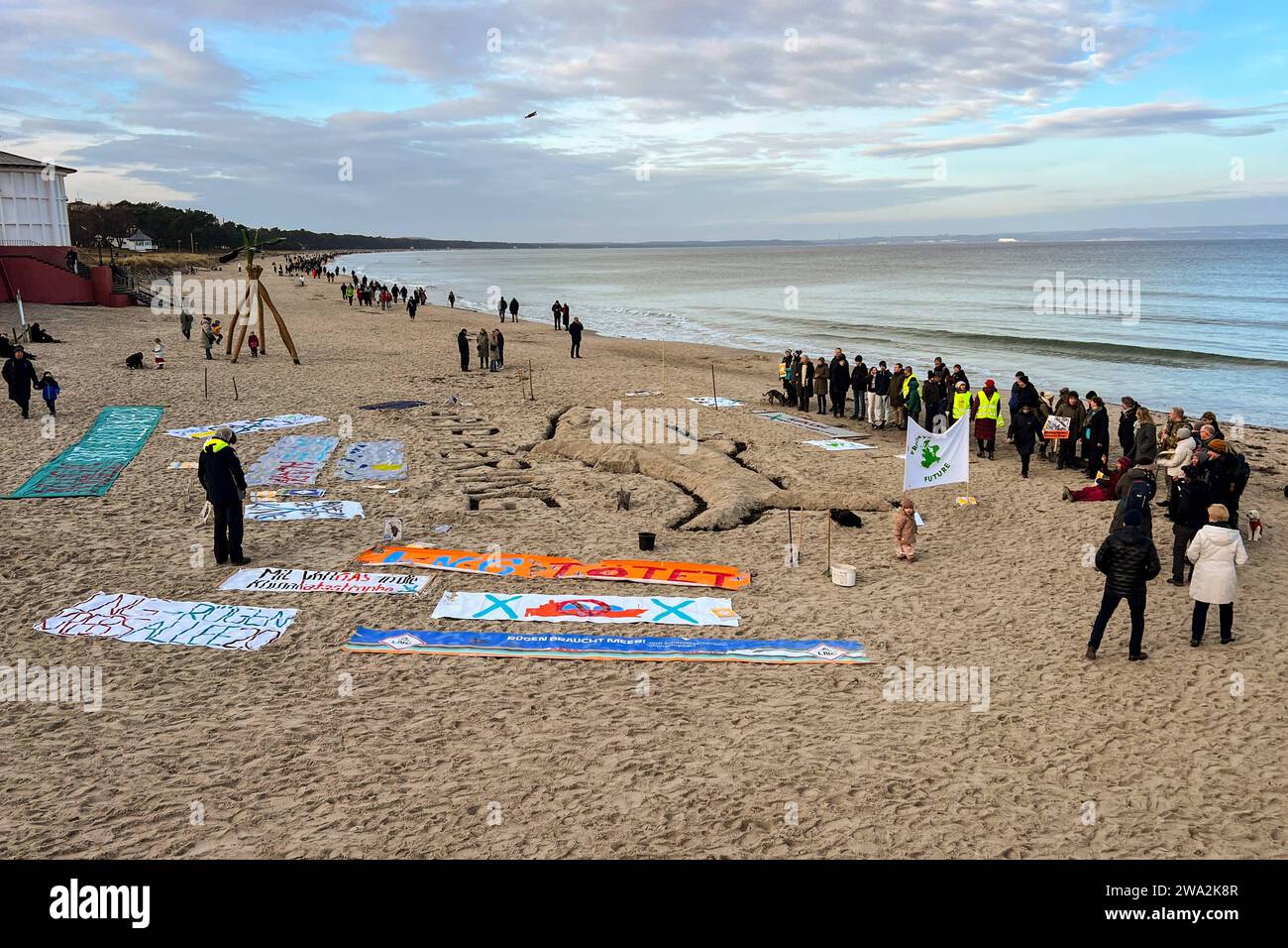 AM Neujahrstag 01.01.2024 findet ein Protest am Strand neben der Seebrücke vom Ostseebad Binz Mecklenburg-Vorpommern statt.Die Bürgerbewegung protestiert gegen LNG Terminals vor der Prorer Wiek. Unter anderem hängen sie Banner an der Seebrücke auf und schaufeln mit Spaten RIP Hering in den Ostseesand. *** Le jour de l'an 01 01 2024, une manifestation a lieu sur la plage à côté de la jetée de la station balnéaire de la mer Baltique de Binz Mecklenburg-Vorpommern le mouvement citoyen proteste contre les terminaux GNL au large du Prorer Wiek entre autres choses, ils accrochent des bannières sur la jetée et pelletent le hareng RIP dans le B. Banque D'Images