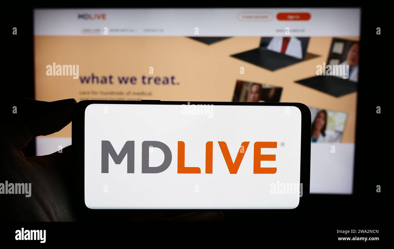 Personne tenant le téléphone portable avec le logo de la société de services de santé virtuelle américaine MDLIVE devant la page Web de l'entreprise. Concentrez-vous sur l'affichage du téléphone. Banque D'Images