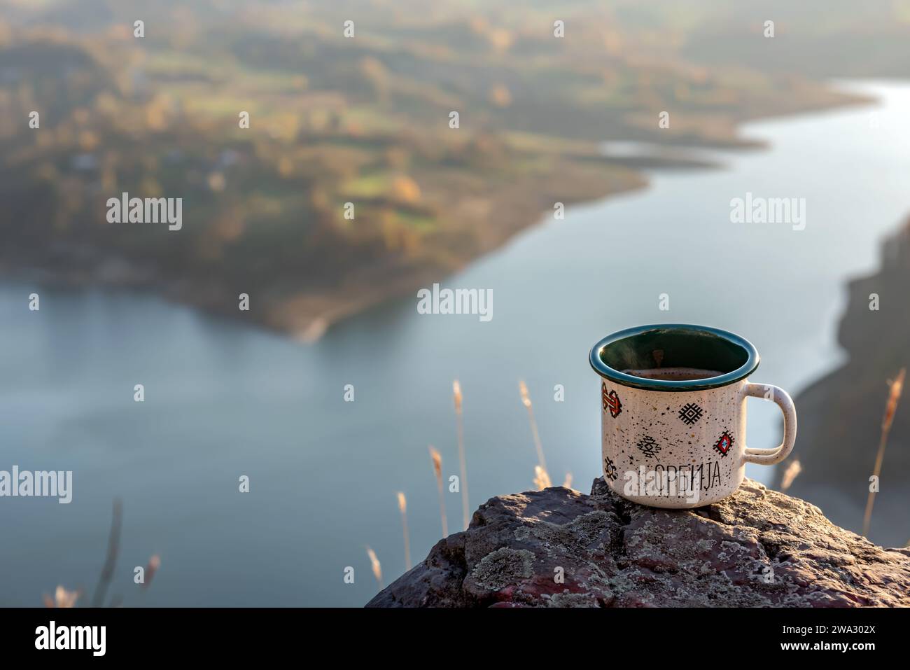 Tasse à café émaillé sur le rocher au point de vue surplombant le lac avec espace de copie pour le texte. Mise au point sélective. Banque D'Images Tasse à café émaillé sur le rocher au point de vue surplombant le lac avec espace de copie pour le texte. Mise au point sélective. Banque D'Images