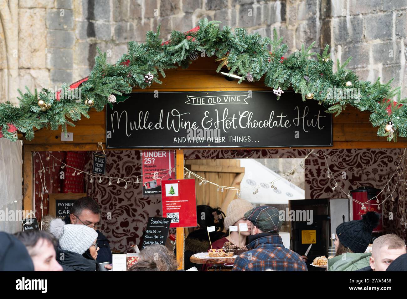 Les clients assoiffés font la queue pour du vin chaud et du chocolat chaud à la cabane à vin chaud « The Old Vine » au marché de Noël de la cathédrale de Winchester. Angleterre Banque D'Images