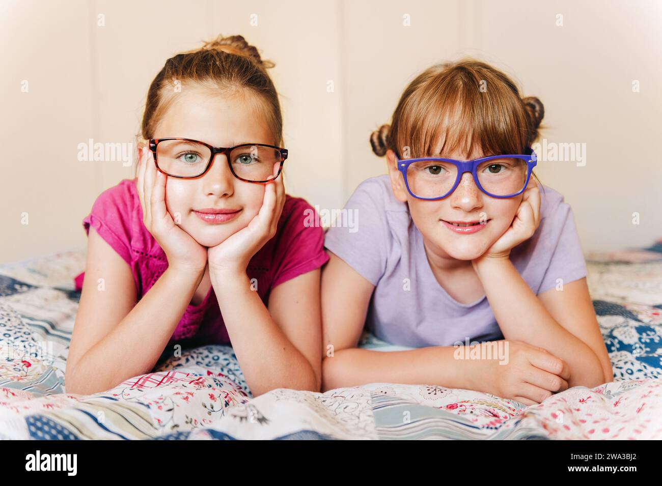 Portrait de 2 filles drôles reposant sur le lit, portant des lunettes Banque D'Images