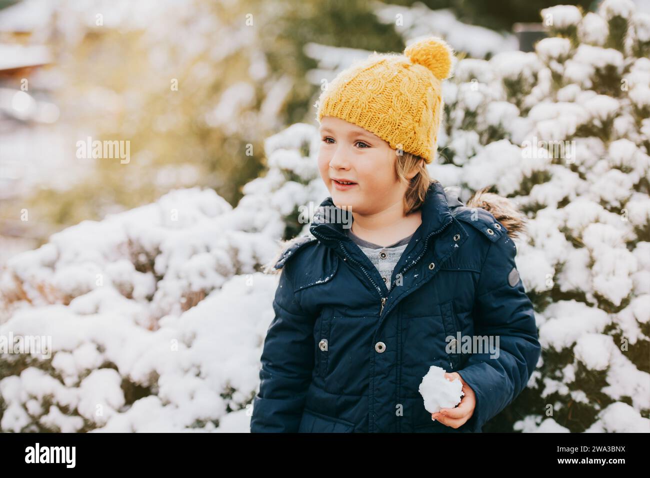 Portrait en plein air d'un jeune garçon de 6 ans portant une veste et des bottes chaudes, profitant de l'hiver Banque D'Images