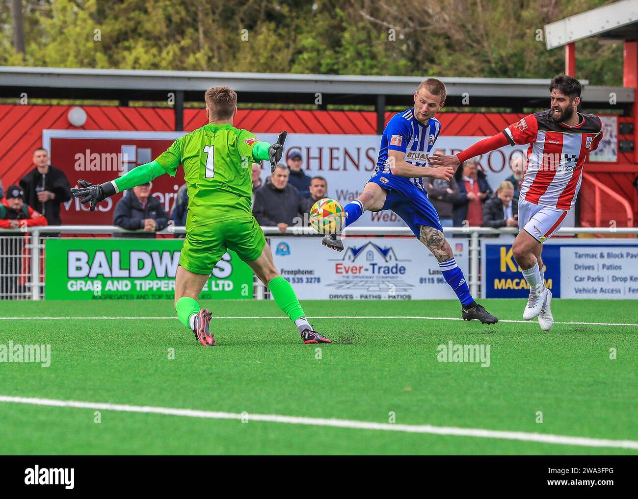 Le milieu de terrain de Nuneaton Borough Charlie Dowd tente de passer le ballon devant le gardien de but d'Ilkeston Town. Banque D'Images
