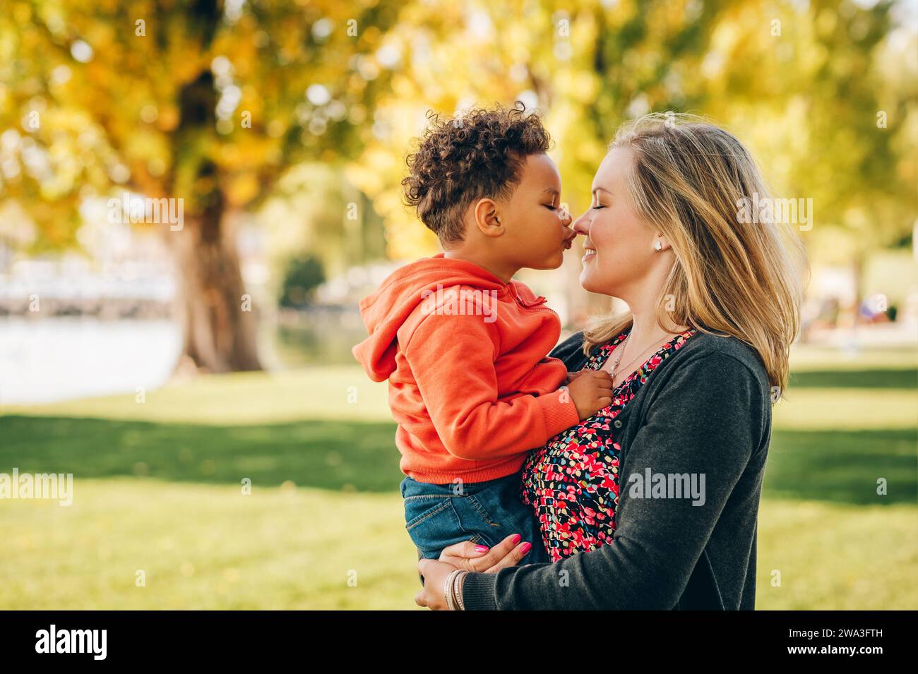 Heureuse jeune mère tenant doux garçon en bas âge, famille s'amusant ensemble à l'extérieur sur une belle journée ensoleillée Banque D'Images