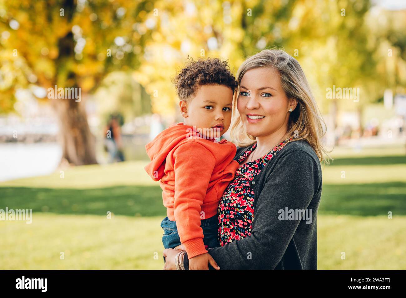 Heureuse jeune mère tenant doux garçon en bas âge, famille s'amusant ensemble à l'extérieur sur une belle journée ensoleillée Banque D'Images