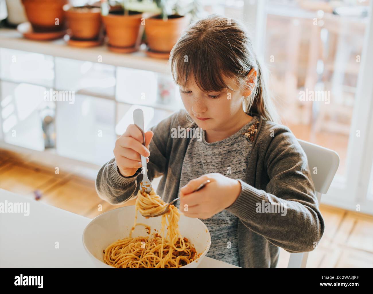 Petite fille mangeant des spaghetti bolognaise à la maison pour le déjeuner Banque D'Images