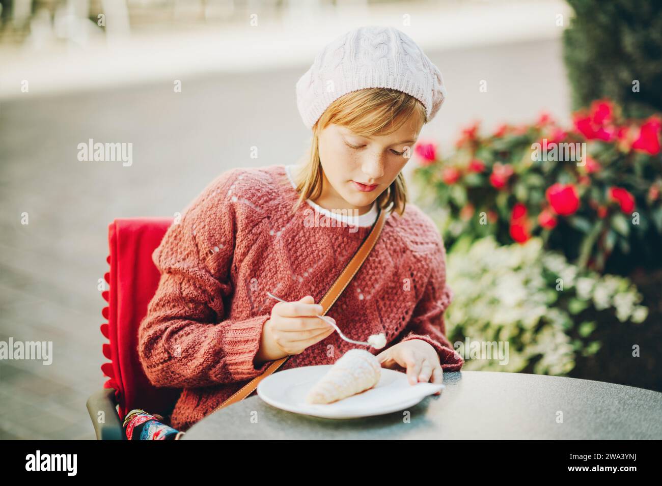 Jolie petite fille se reposant dans un café, mangeant du gâteau sucré Banque D'Images