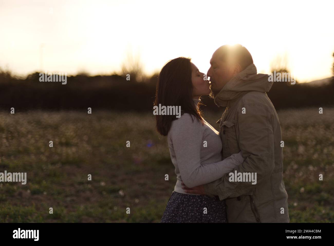 Un homme embrasse et embrasse sa petite amie au coucher du soleil dans un environnement naturel. Banque D'Images
