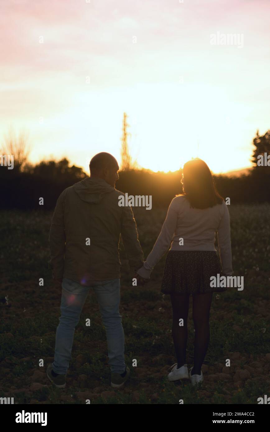 Couple de mariage se tenant la main tout en regardant le coucher de soleil à l'horizon. Banque D'Images