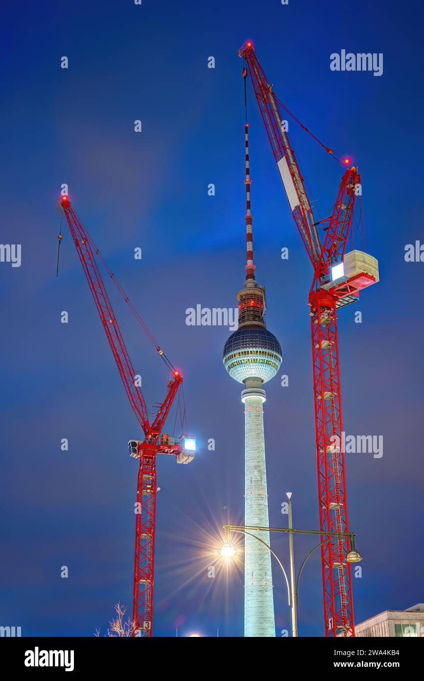La célèbre tour de télévision de Berlin au crépuscule avec deux grues de construction rouges Banque D'Images