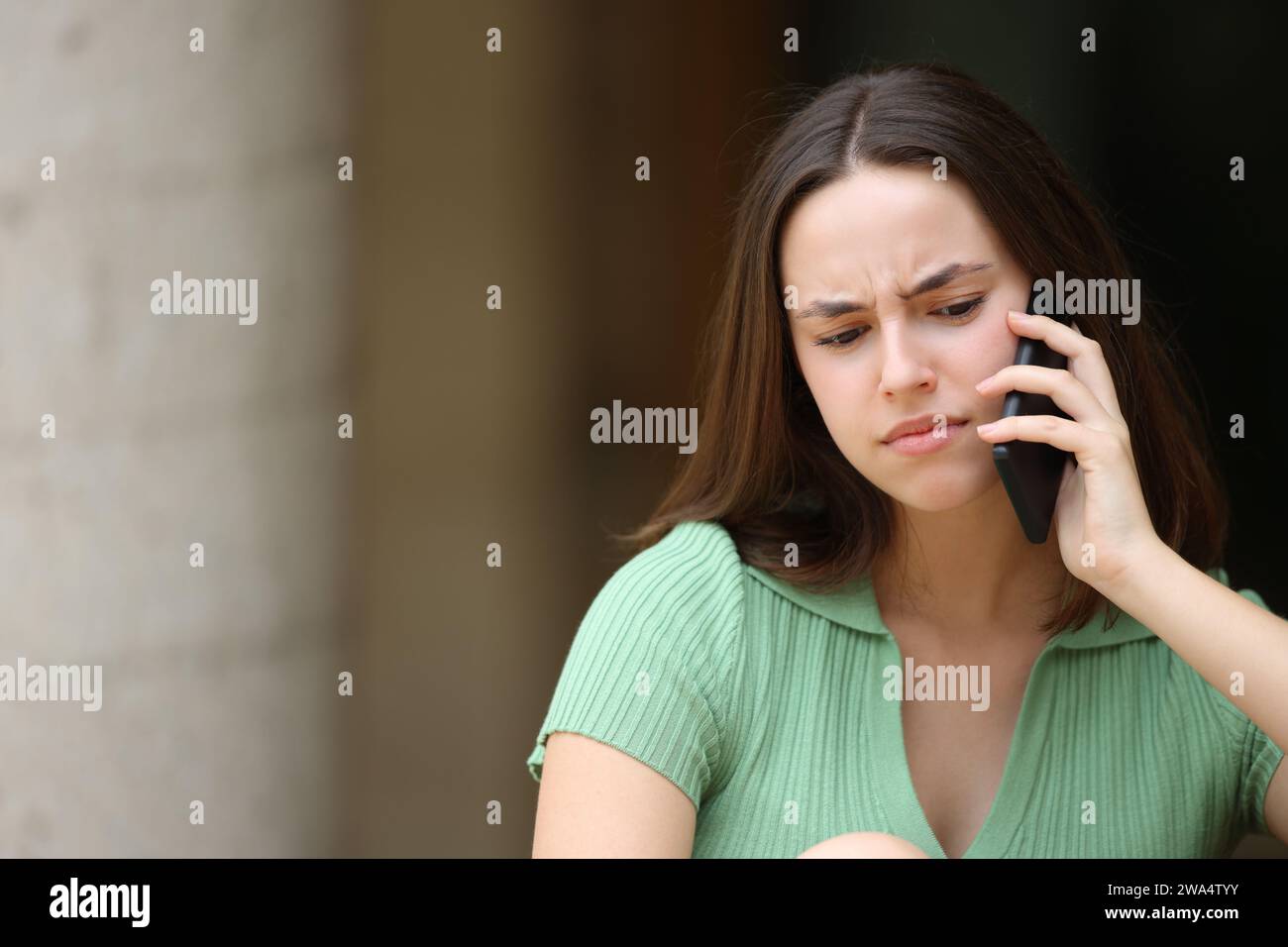Femme confuse parlant au téléphone dehors dans la rue Banque D'Images