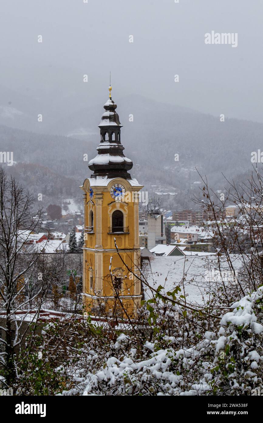 Le clocher avec l'horloge de l'église catholique sur fond de montagnes enneigées Banque D'Images