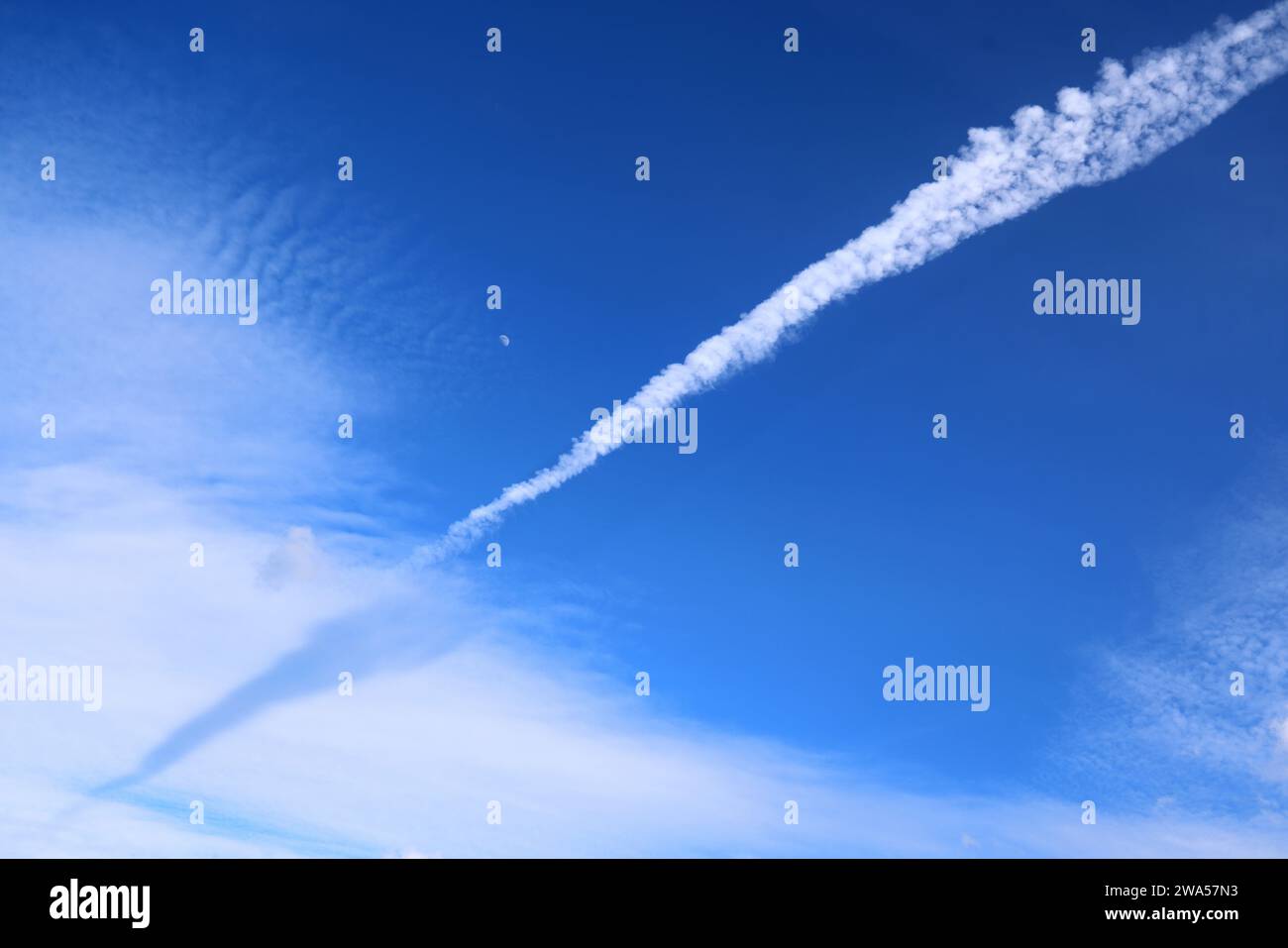 Un jet Airliner contrail, à travers un ciel bleu avec Moon, au-dessus de Cheltenham, Gloucestershire. - 10 mai 2022 photo de Andrew Higgins/Thousand Word Media L. Banque D'Images