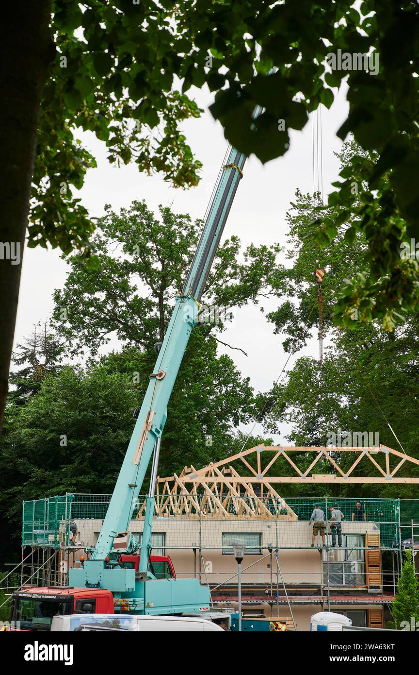 Bauhandwerk, Hausbau, Kran hebt Holzständerteile auf Rohbau für die Dachkonstruktion, Hochformat Arbeitsmittel *** Bâtiment, construction de maisons, grue soulève des pièces de charpente en bois sur la carcasse pour la construction de toits, matériel de travail au format portrait Banque D'Images