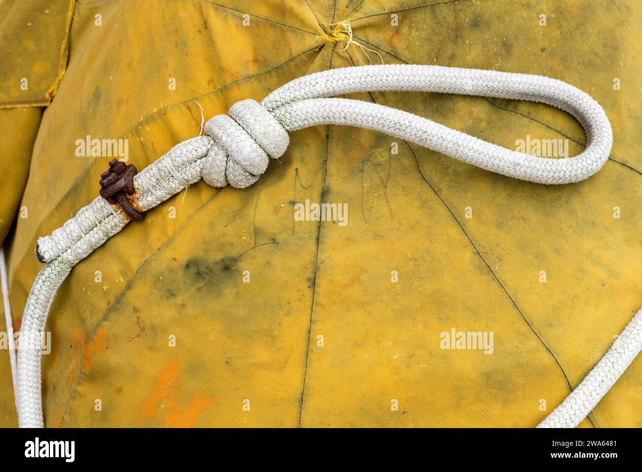 Gros plan d'une corde avec un nœud pour une fixation rapide sur le port de Grado, Italie. Articles pour bateaux de pêche. Fond réaliste avec une bâche jaune Banque D'Images