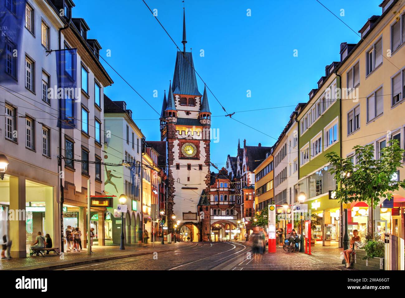 Scène nocturne le long de Kaiser-Joseph-Straße avec Martinstor, l'une des deux portes restantes de la ville médiévale de Fribourg im Breisgau, Allemagne. Banque D'Images