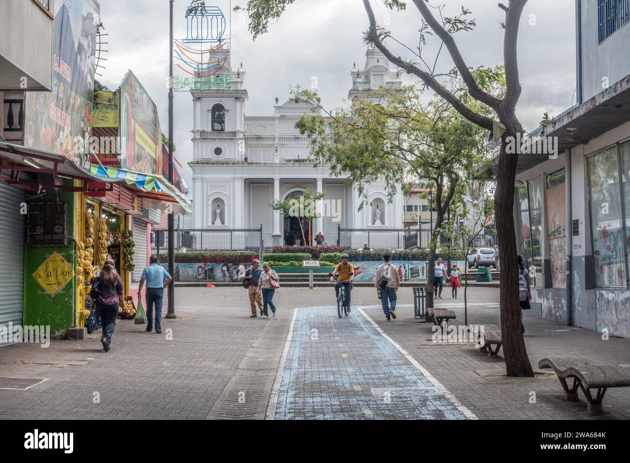 Personnes dans une rue piétonne devant une église (église Soledad) à San José, Costa Rica. Banque D'Images