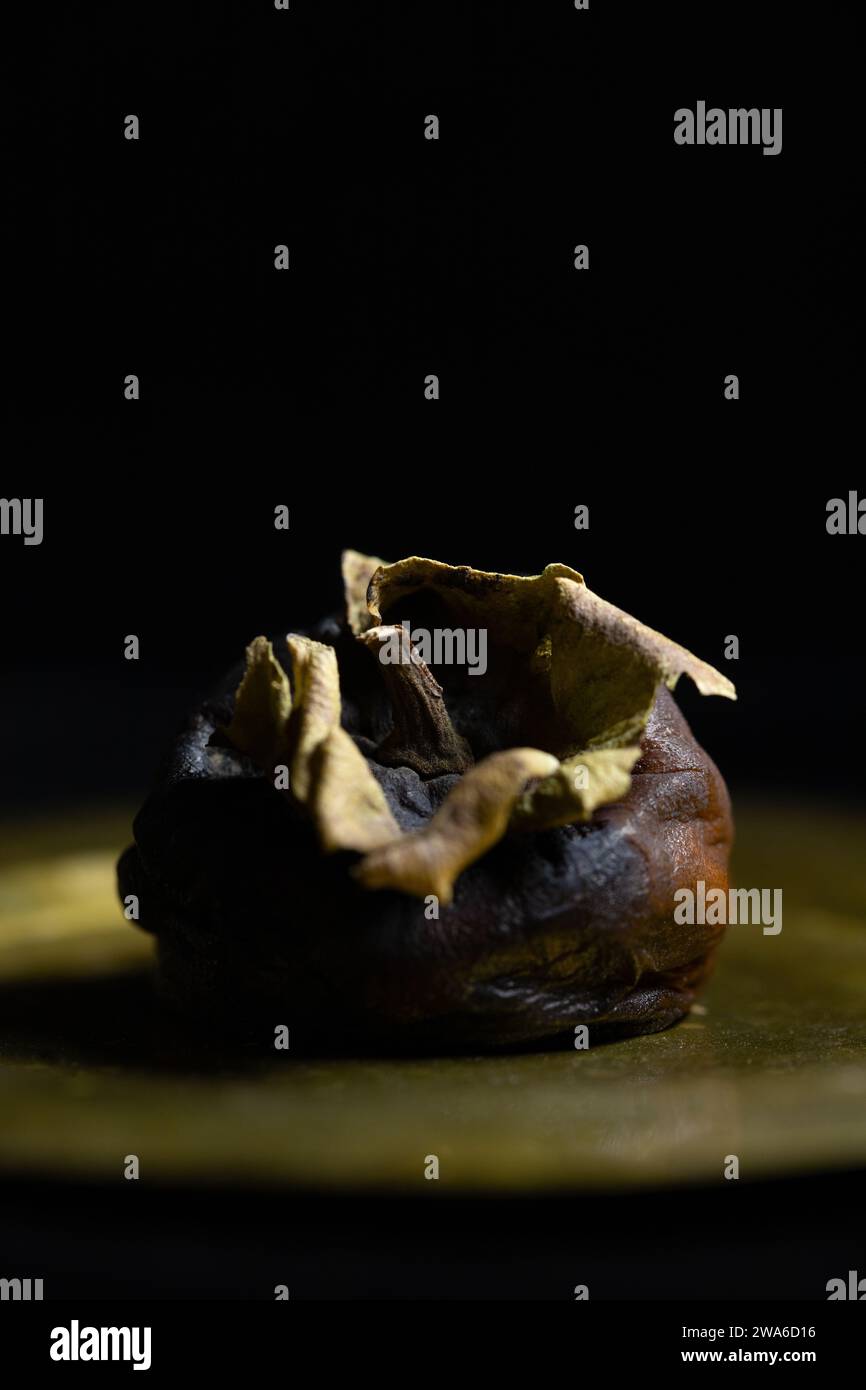 Un vieux kaki en décomposition sur une assiette. Banque D'Images