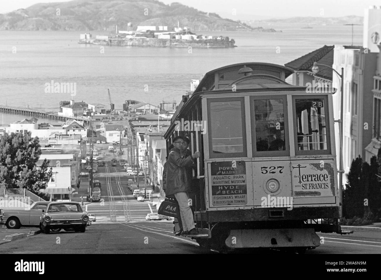 Eine für San Francisco typische Straßenbahn fährt die Hyde Street hügelabwärts, im hintergrund ist Alcatraz Island sichtbar, dessen berüchtigtes Gefängnis 1963 geschlossen wurde, San Francisco 1962. Un téléphérique typique de San Francisco descend sur Hyde Street, l'île d'Alcatraz, dont la prison notoire a été fermée en 1963, est visible en arrière-plan, San Francisco 1962. Banque D'Images