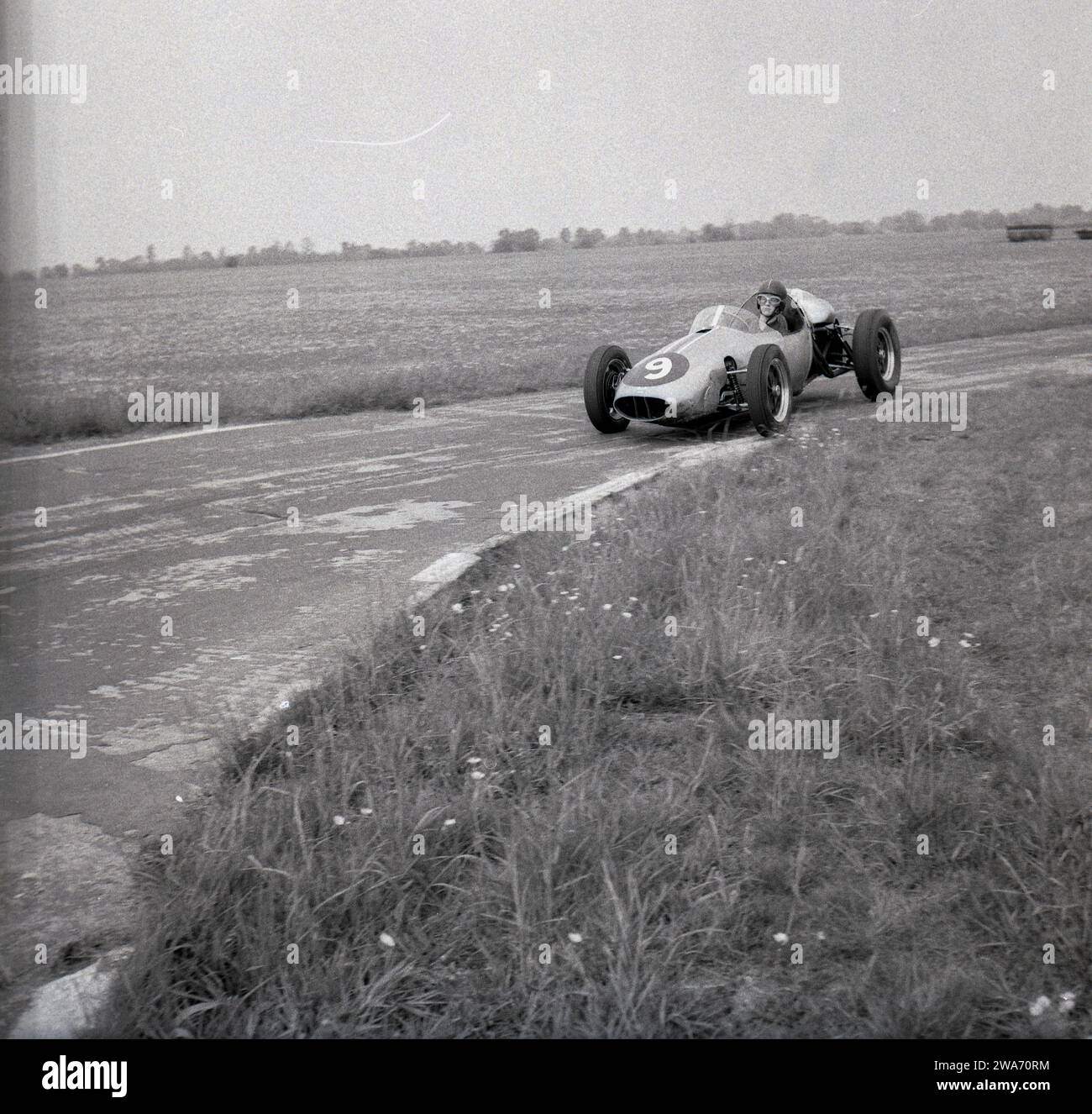 1962, historique, pilote stagiaire dans une monoplace 'Cooper' sur le circuit de l'aérodrome de Finmere, Buckinghamshire, Angleterre, Royaume-Uni, l'emplacement des écuries de course automobile de Geoff Clarke. RAF Finmere était une base de bombardiers de la Seconde Guerre mondiale, qui avec trois pistes, avait une grande route de périmètre et c'est celle qui a été utilisée pour le circuit de l'école automobile, qui a vu les élèves conduire des monoplaces Cooper à roues ouvertes alors qu'ils apprenaient à courir des voitures. Banque D'Images