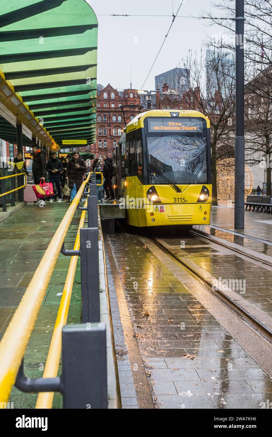 Le 2 janvier 2024, les passagers quittent un tramway jaune sous la pluie à la gare St Peters Square sur le réseau de transport Manchester Metrolink. Banque D'Images