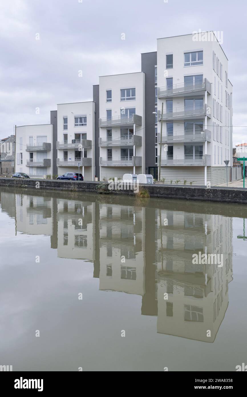 Nancy, France - Focus sur un complexe immobilier résidentiel moderne avec des reflets sur l'eau dans un canal. Banque D'Images