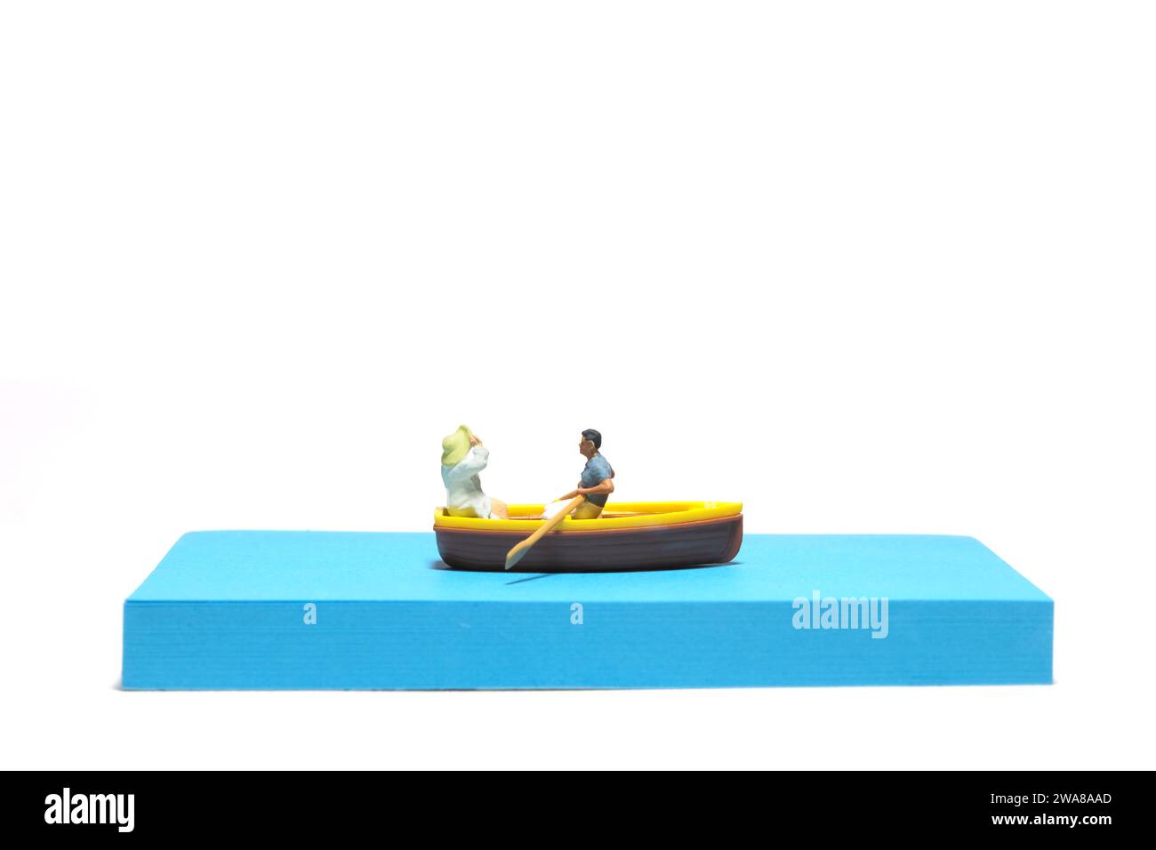 Photographie de figurine miniature créative de personnes. Installation de notes autocollantes. Un couple datant sur un bateau à la mer du lac de rivière. Isolé sur fond blanc Banque D'Images