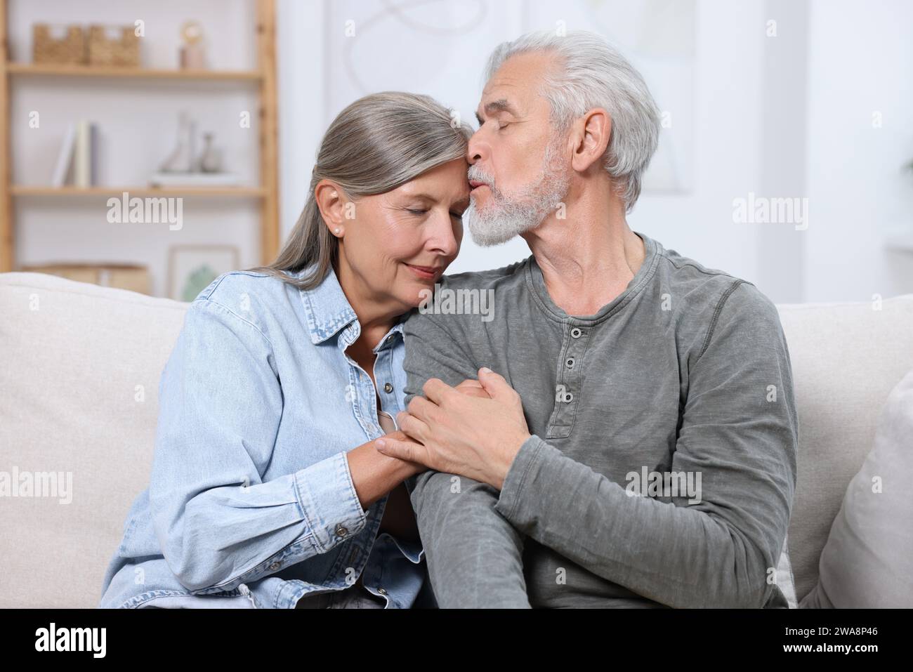 Homme senior embrassant sa femme bien-aimée à la maison Banque D'Images