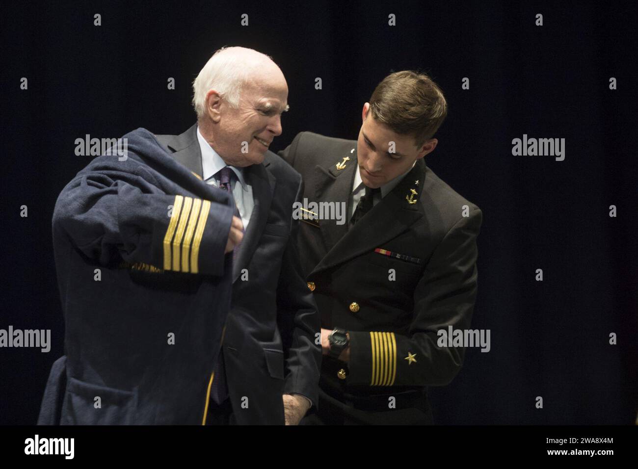 Forces militaires AMÉRICAINES. 171030DY073-0373 ANNAPOLIS, MD (30 octobre 2017) aspirant de marine de 1e classe Austin Harmel, commandant de brigade de l'Académie navale des États-Unis (USNA), présente au sénateur John McCain un peignoir de bain personnalisé au nom de la brigade d'aspirant de marine. McCain a visité l'USNA pour parler aux midshipmen de ses expériences pendant la Seconde Guerre mondiale et de l'état actuel des affaires mondiales. (Photo de l'US Navy par Brianna Jones, spécialiste des communications de masse de 2e classe/publiée) Banque D'Images