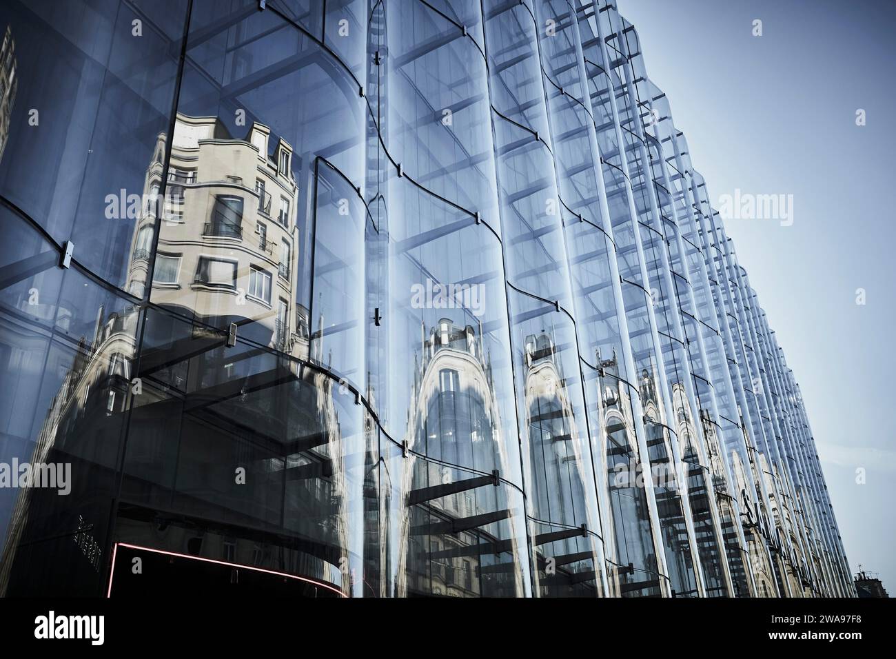 La façade ondulée d'un grand bâtiment de la ville de Paris reflète les maisons en face, rue de Rivoli Banque D'Images