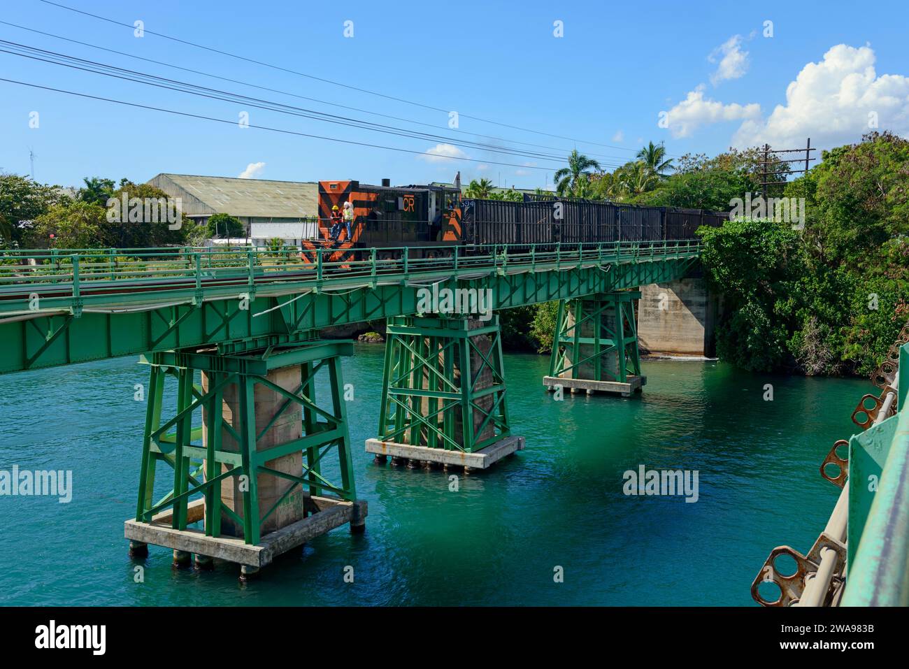 Un train traverse un pont vert sur l'eau bleu-vert clair sur une journée ensoleillée, chemin de fer sur le pont ferroviaire, rivière Dulce, la Romana, République Dominicaine, HISP Banque D'Images