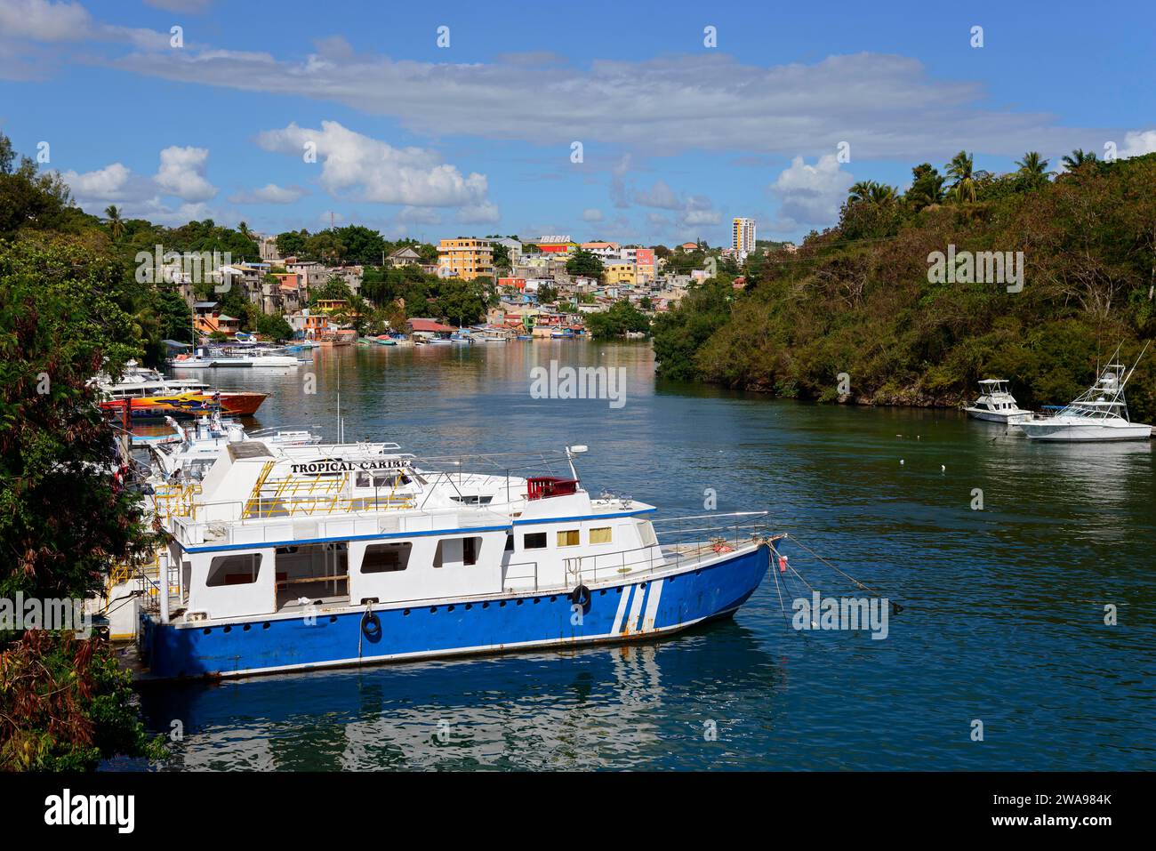 Vue d'une rivière avec des bateaux et une ville en arrière-plan sur une journée ensoleillée, Dulce River, la Romana, République Dominicaine, Hispaniola, Caraïbes, AME centrale Banque D'Images