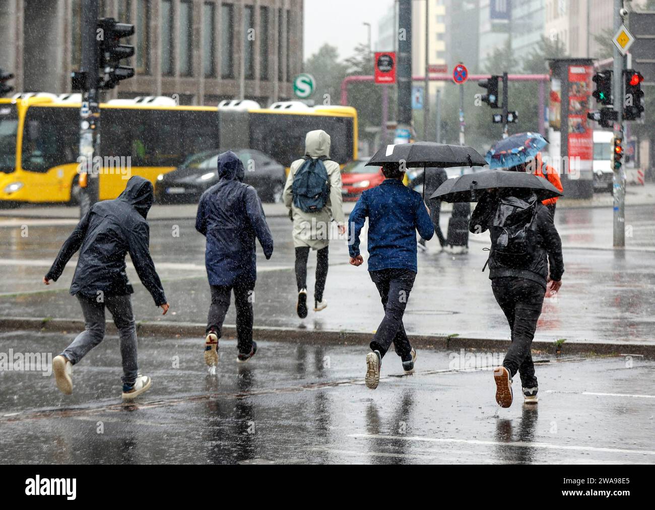 Les gens en tenue de pluie courent dans une rue sous de fortes pluies Berlin, 23 06 2023 Banque D'Images
