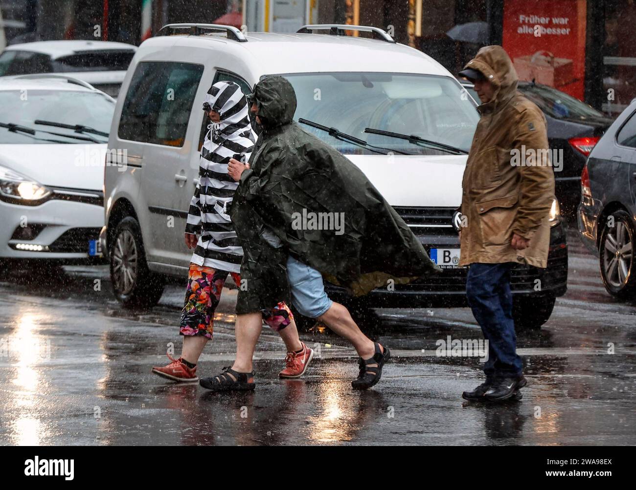 Des gens en tenue de pluie marchant dans une rue sous de fortes pluies, Berlin, 23 06 2023 Banque D'Images