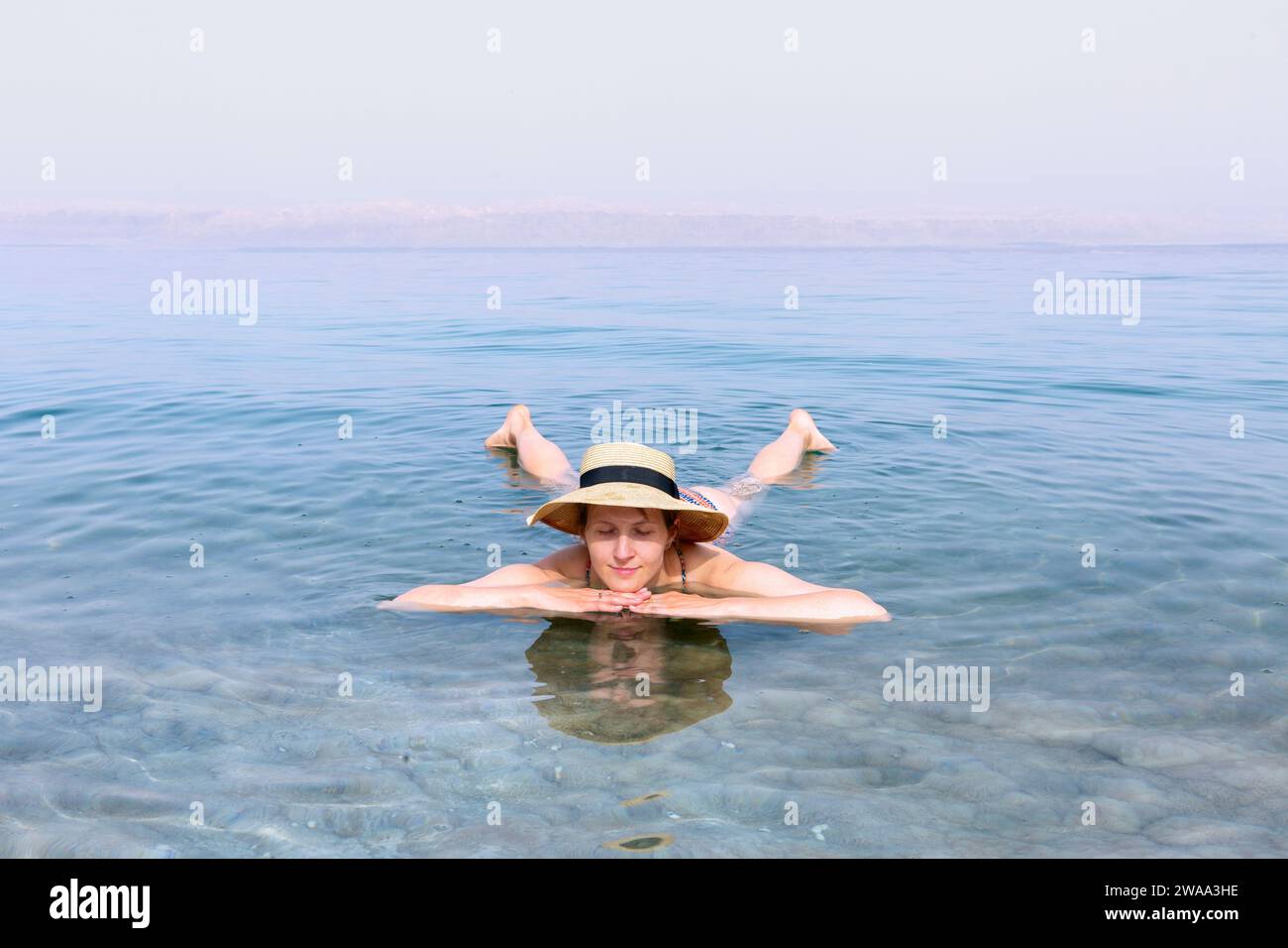 Femme avec chapeau se relaxant dans l'eau salée d'une mer Morte Banque D'Images