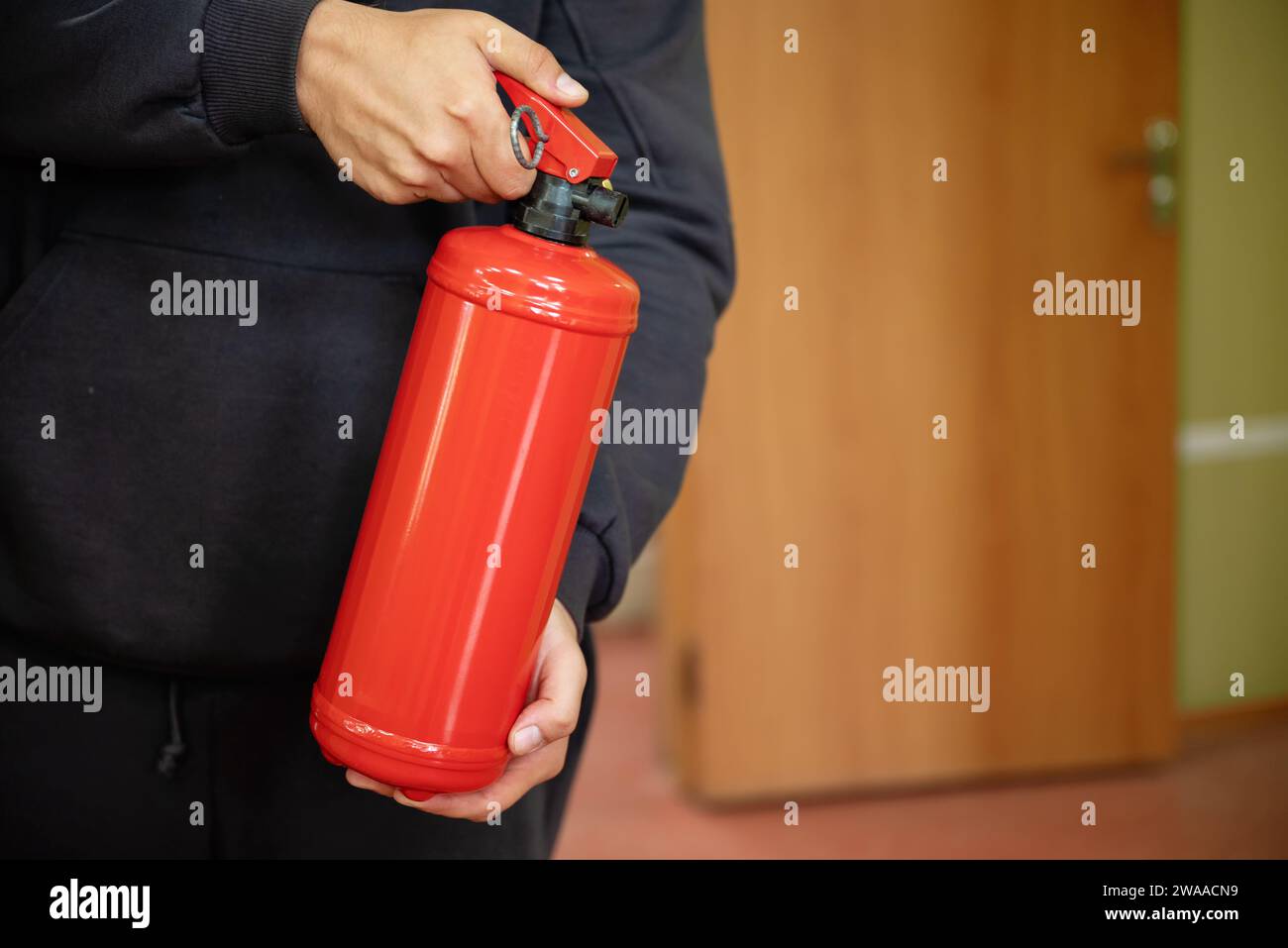Un homme tient un extincteur dans le bureau. Le concept de sécurité incendie Banque D'Images
