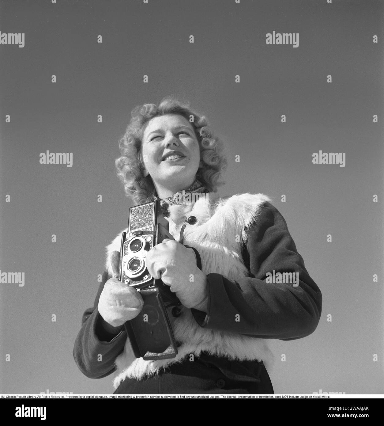 Hiver dans les années 1940 Une jeune femme photographie un jour d'hiver. La caméra est un Rolleiflex de la société allemande Rollei pour film 60 mm. 1944. Photo Kristoffersson Réf. F104-5 Banque D'Images