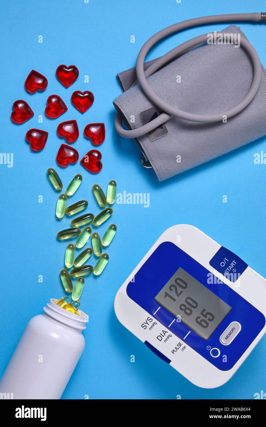 Vitamine D et coeurs décoratifs rouges et tonomètre cardiaque sur fond bleu. Prévention et traitement de l'athérosclérose, de l'hypertension et de l'ischémie Banque D'Images