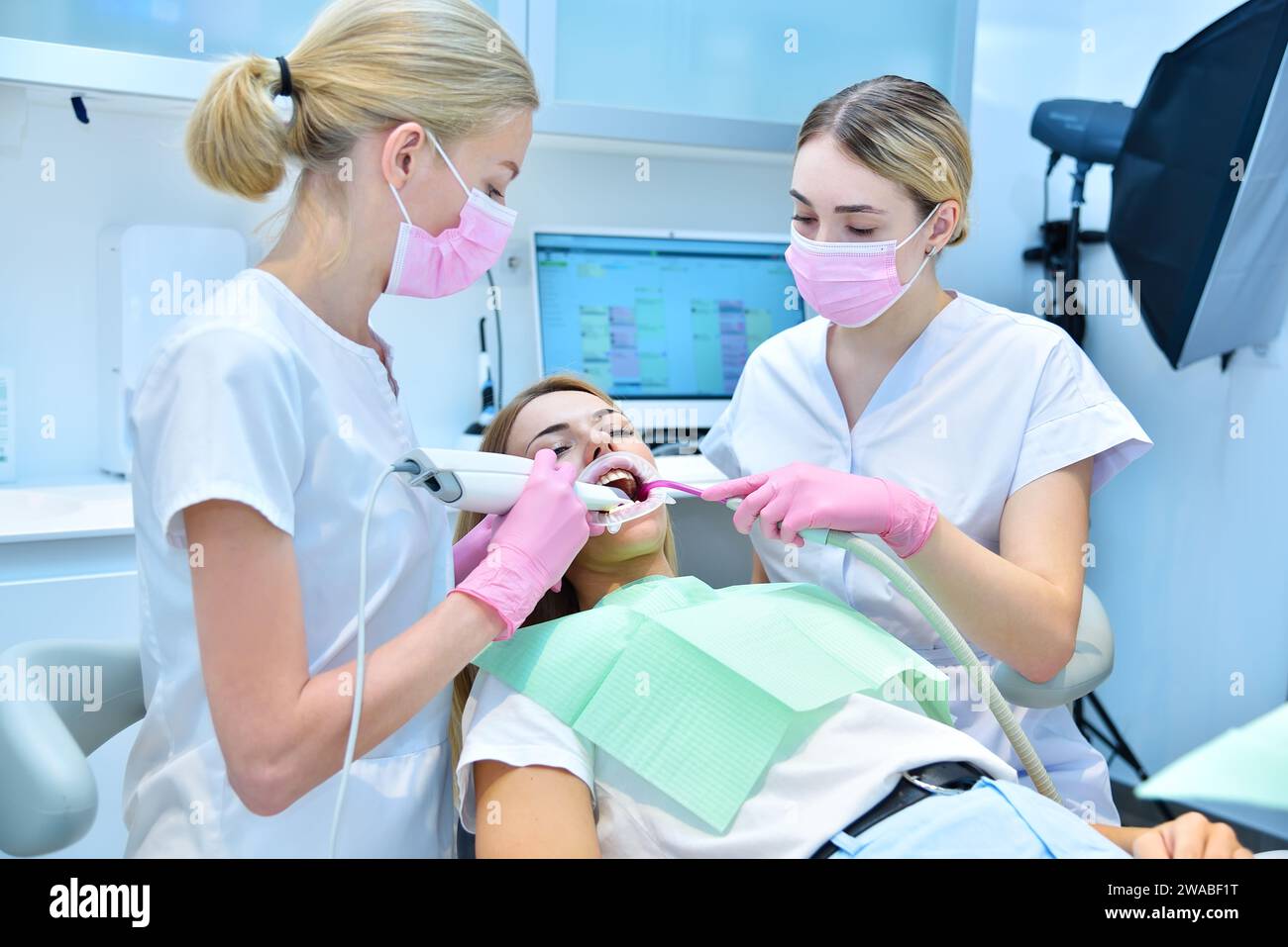 Orthodontiste et assistant à l'examen des dents d'un patient au scanner 3d intra-oral en clinique. Concept de soins de santé et stomatologie Banque D'Images