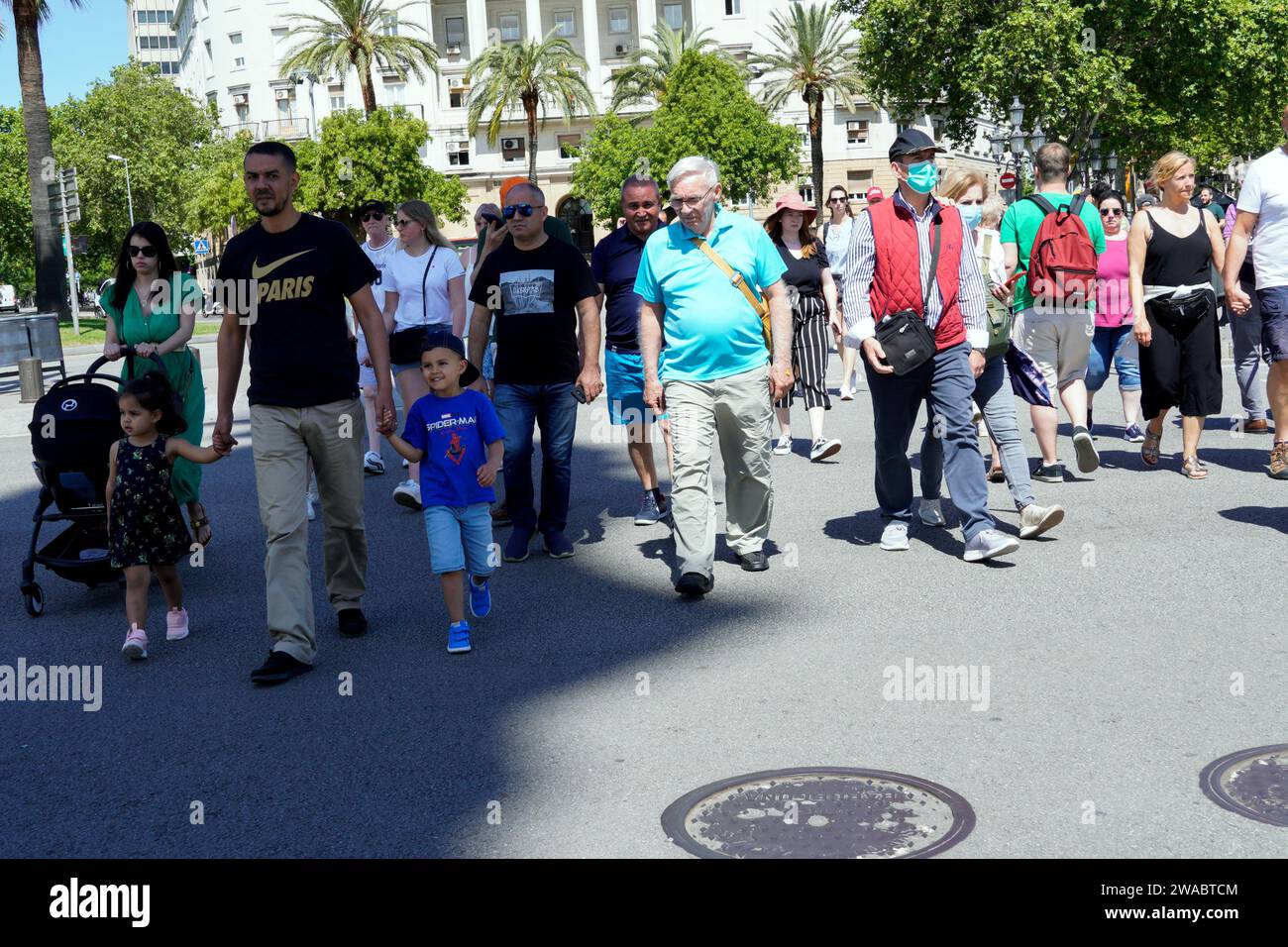 Barcelone, Espagne - 26 mai 2022 : un groupe important et varié de personnes traversent la route achalandée de Barcelone, visages préoccupants sauf l'enfant qui sourit. Banque D'Images