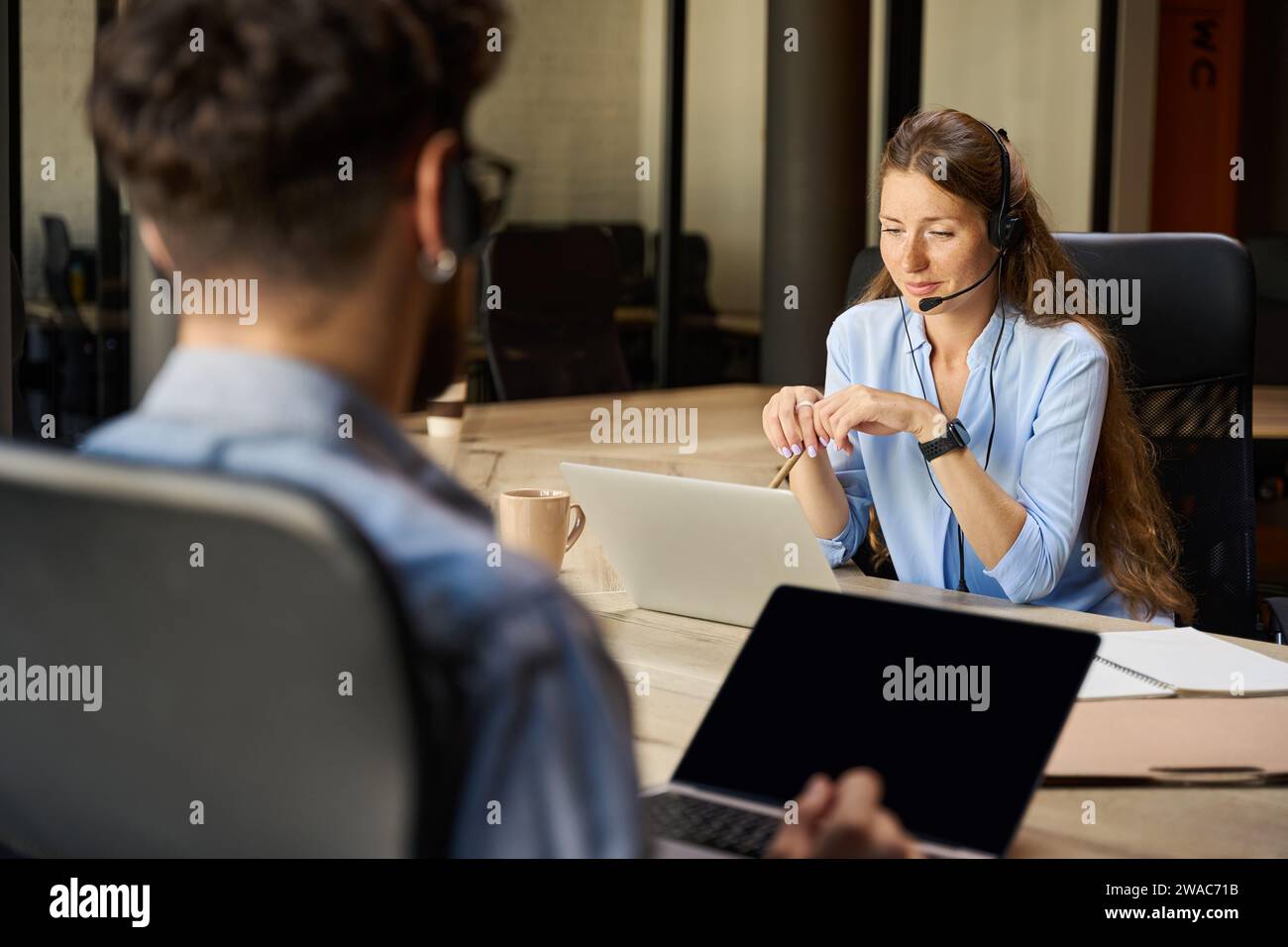 Opérateurs caucasiens sérieux de centre d'appels utilisant des ordinateurs portables dans le bureau de coworking Banque D'Images