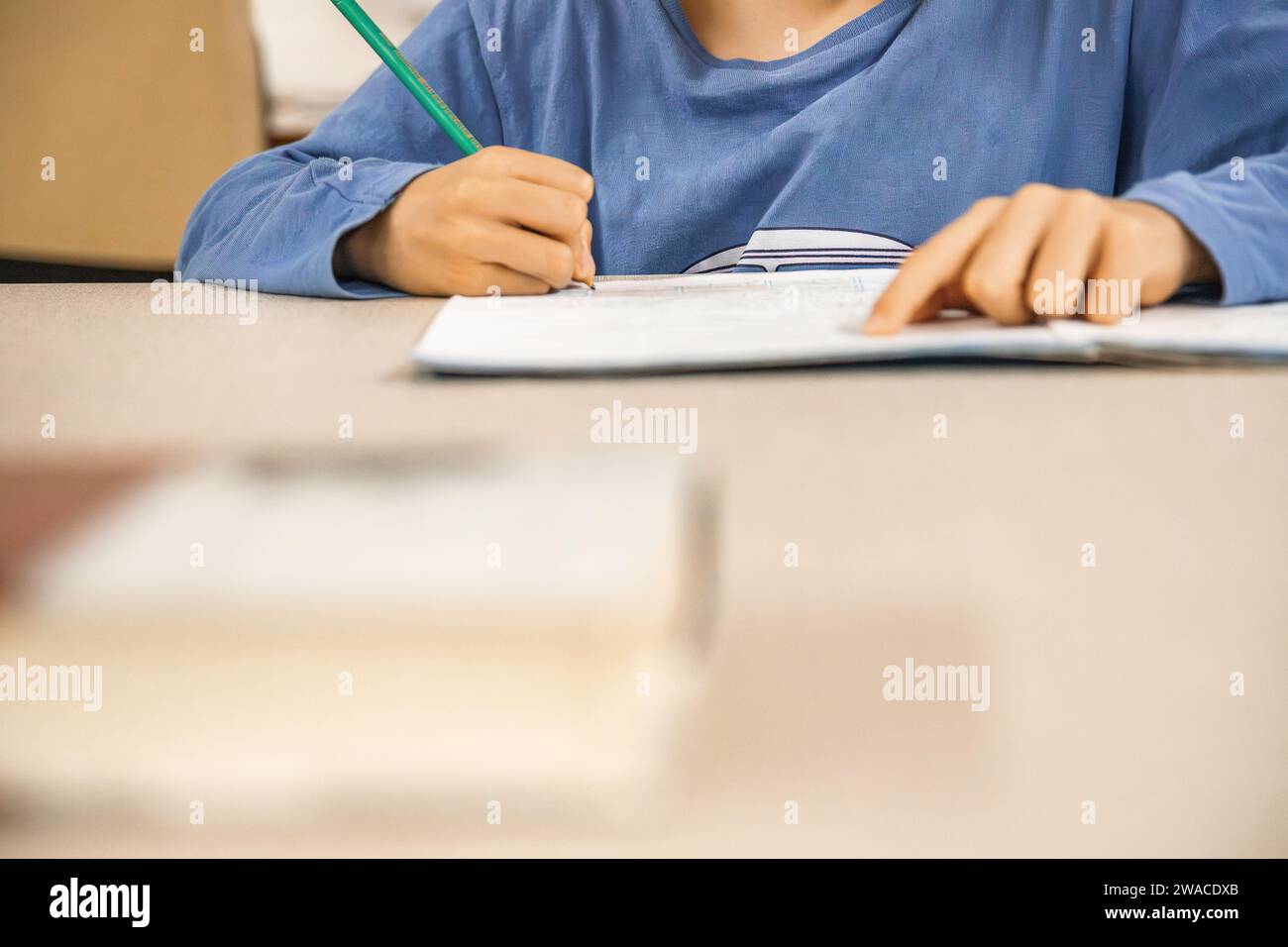 Enfant caucasien de l'école élémentaire faisant ses devoirs à la fin de la journée scolaire. Gros plan et espace de copie. Banque D'Images