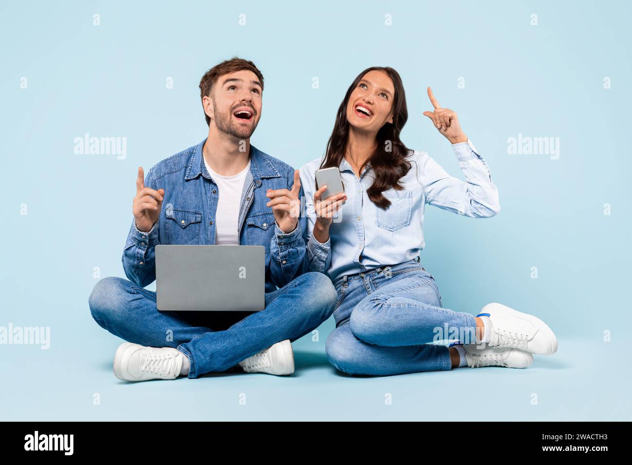 Couple excité avec ordinateur portable et téléphone, ayant un moment eureka Banque D'Images
