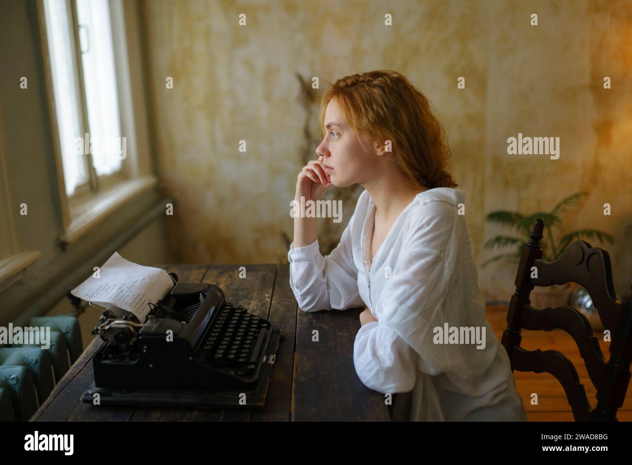 Vue de côté de la femme à l'aide d'une machine à écrire vintage à la maison Banque D'Images
