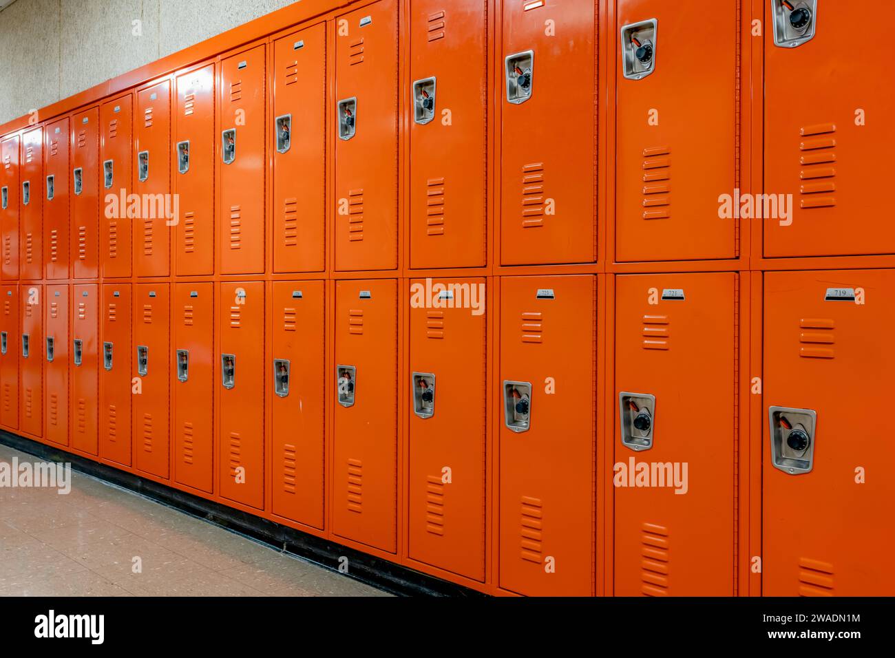 Casiers en métal orange le long d'un couloir indescriptible dans un lycée américain typique. Aucune information identifiable incluse et personne dans le hall. Banque D'Images